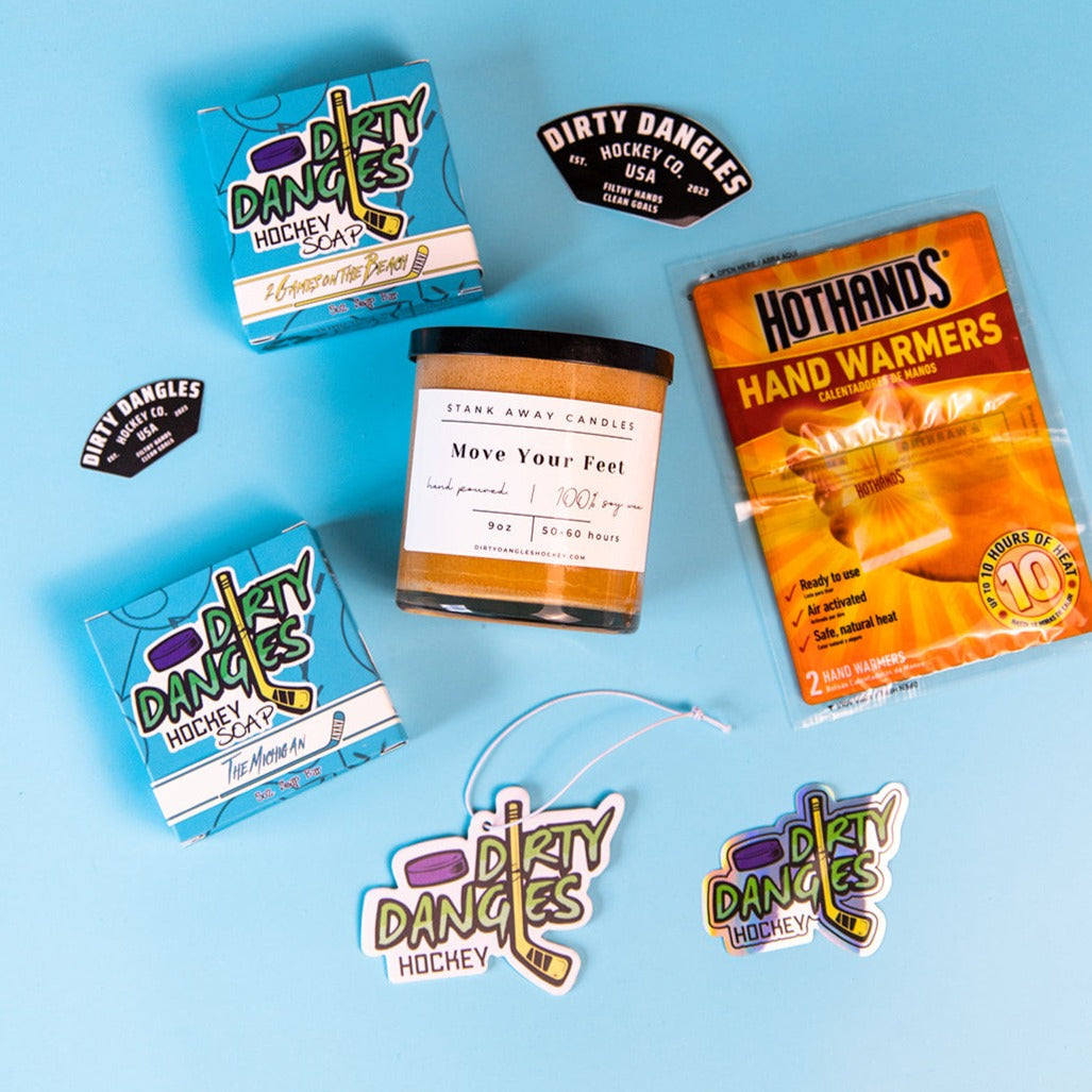 2 dirty dangles hockey soap bars, a soy wax candle, a car air freshener and hand warmers on a blue background with stickers.