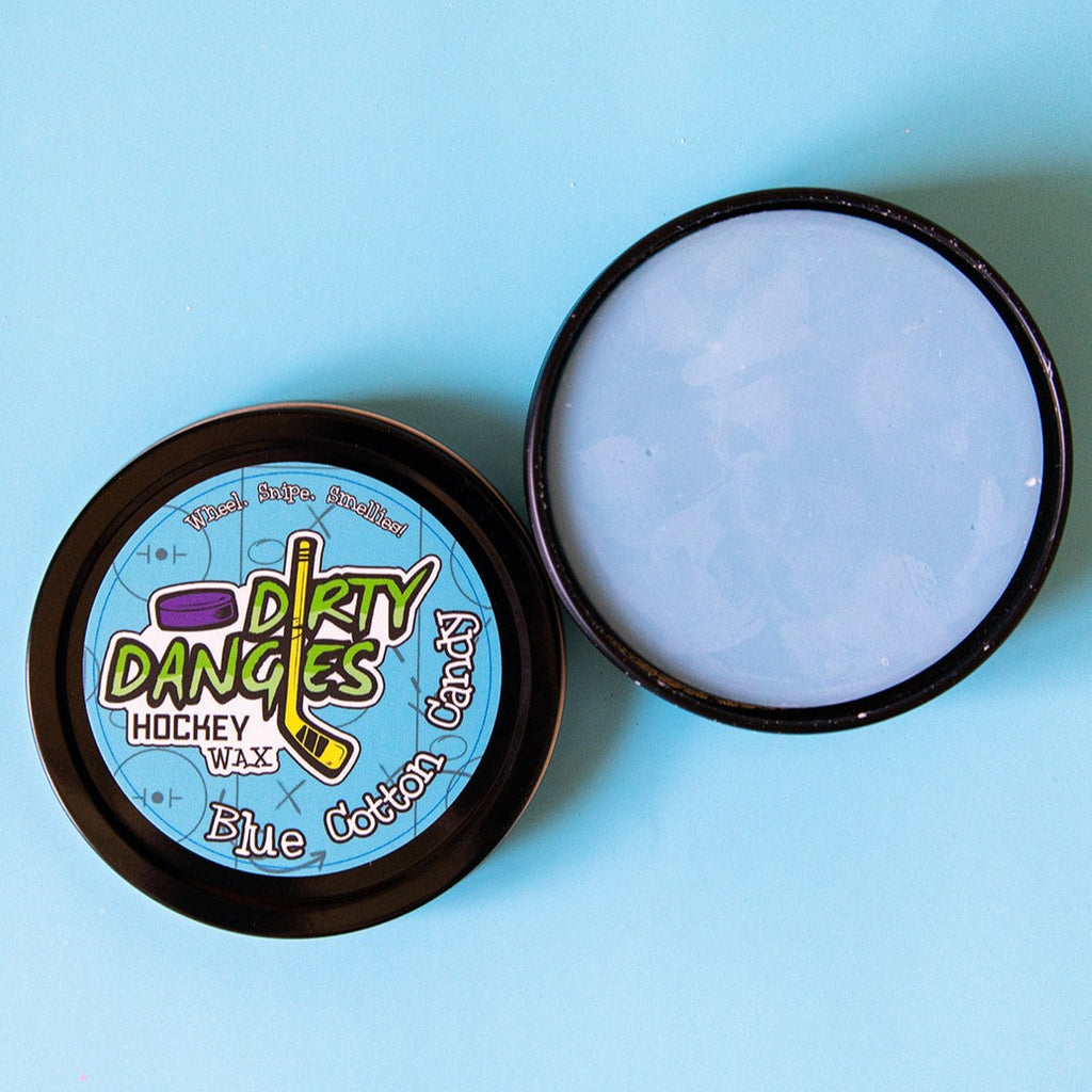 A tin of Dirty Dangles Hockey Stick sits o Wax Blue Cotton Candy Scent sits open on a blue background showing a blue stick wax.