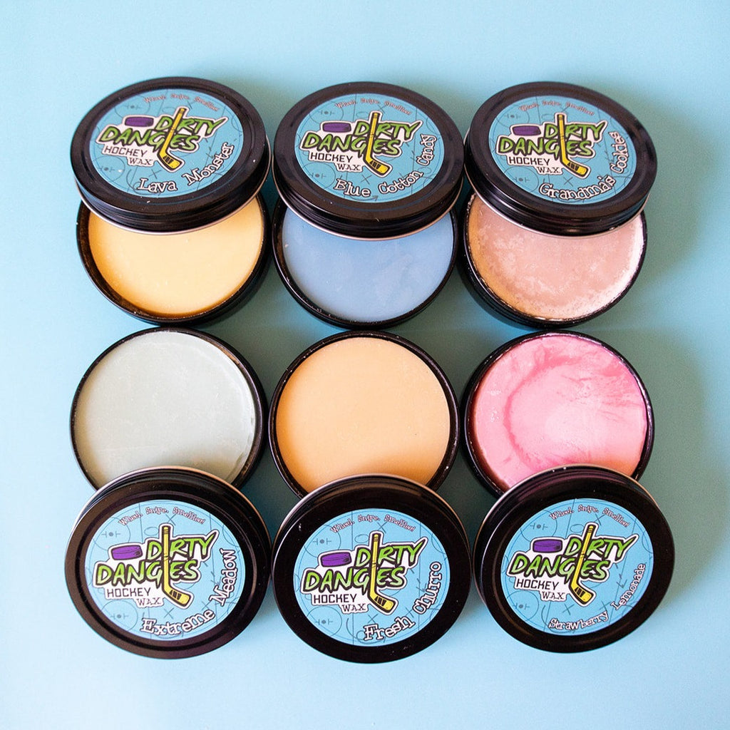 6 open hockey stick wax tins on a light blue background. Dirty dangles hockey stick wax.