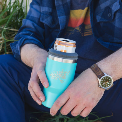 A man holding a blue dirty dangles 2 in 1 drink tumbler can cooler outside.