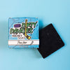 A Black bar of dirty dangles hockey soap Puck Drop scent on a blue background with a blue box