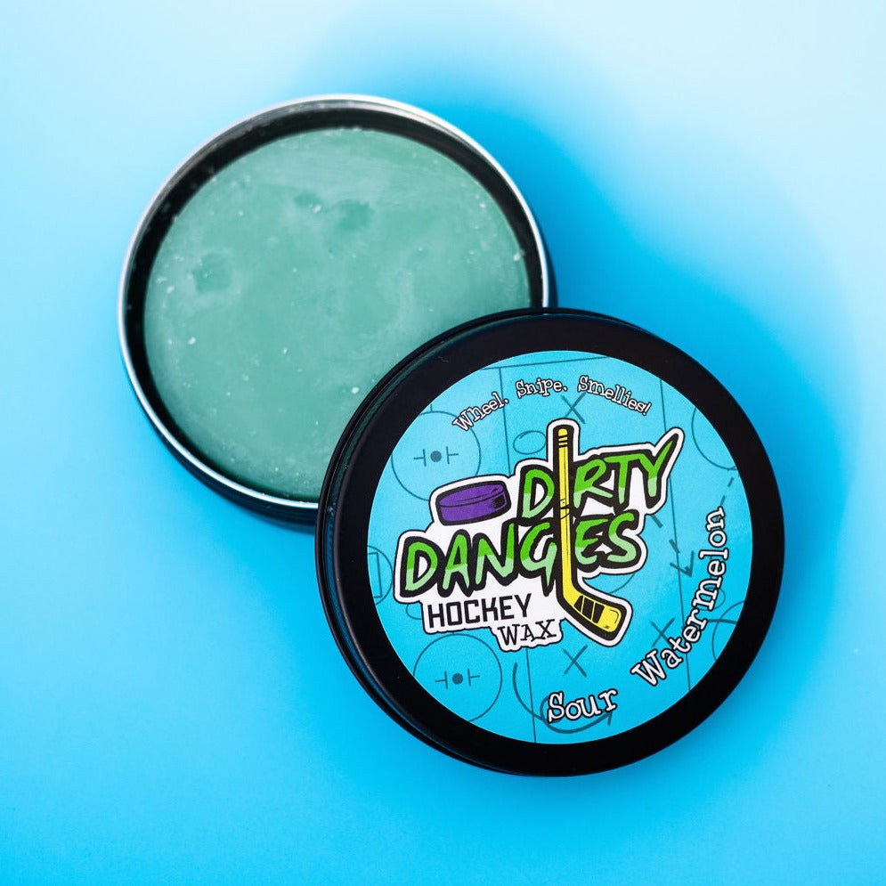A tin of Dirty Dangles Hockey Stick Wax Sour Watermelon scent sits open on a blue background.