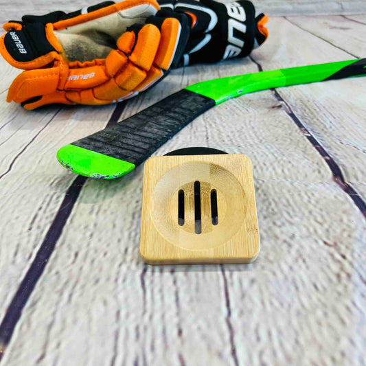 A bamboo soap holder on a wood background with a green hockey stick