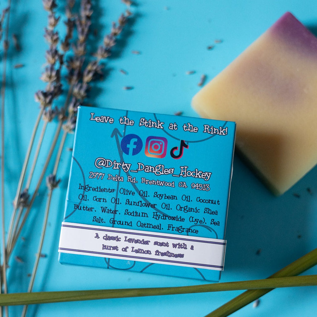 A bar of dirty dangles hockey soap lavender lemongrass scent on a blue background with lavender.