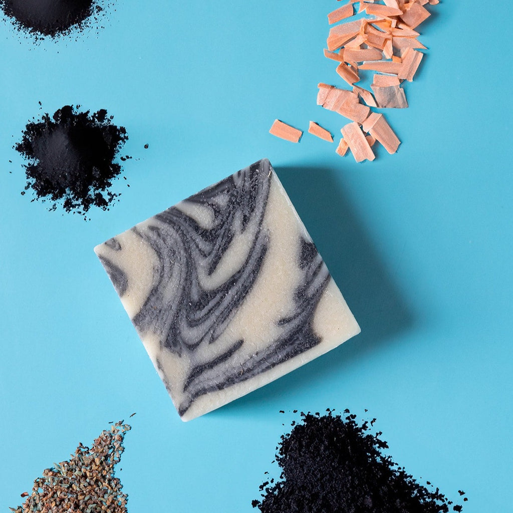A bar of dirty dangles hockey soap silky mitts scent on a blue background with wood, charcoal and lavender