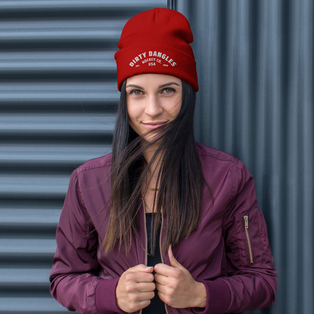 A woman wearing a red dirty dangles hockey co beanie
