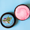 A tin of Dirty Dangles Hockey Stick Wax Strawberry Lemonade scent sits open on a blue background.