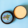 A tin of Dirty Dangles Hockey Stick Wax Lava Monster scent sits open on a blue background.