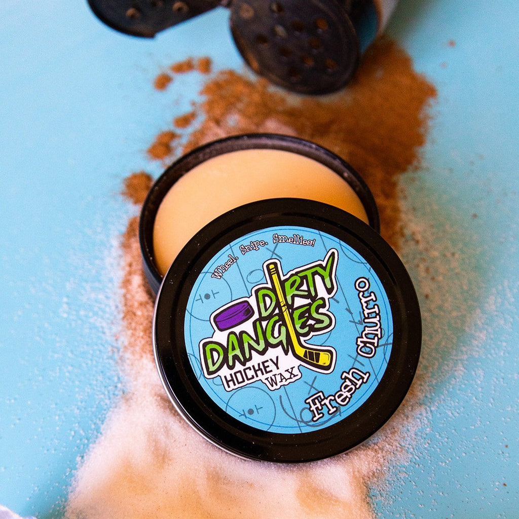 A tin of hockey stick wax against a cinnamon and sugar background. Dirty Dangles Hockey Wax Fresh Churro Scent