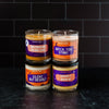 Four Halloween-themed candles stacked against a dark tiled wall.