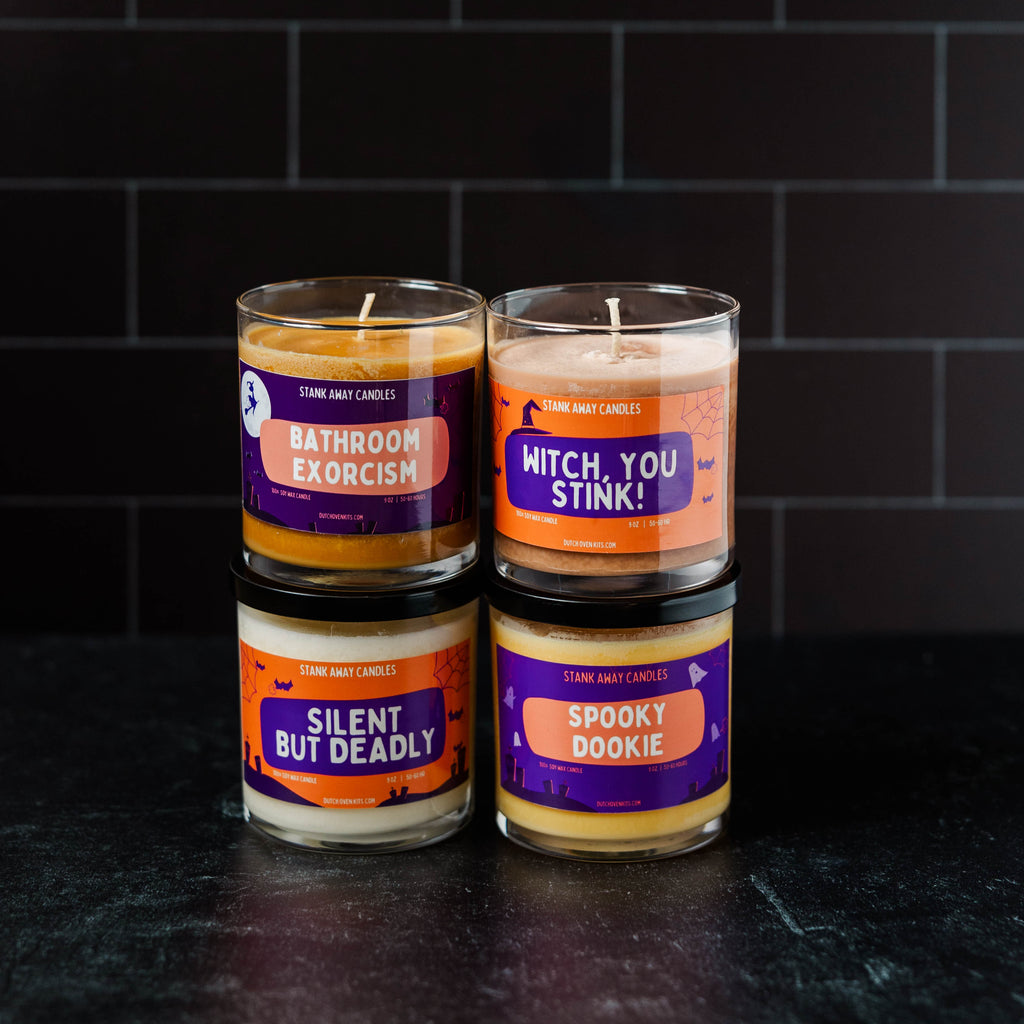 Four Halloween-themed candles stacked against a dark tiled wall.