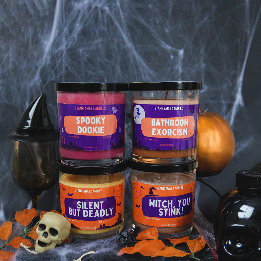 Four Halloween-themed candles on a dark background with spider webs and pumpkins.