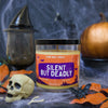 Halloween-themed candle labeled 'Silent But Deadly' with decorative elements on a dark background.