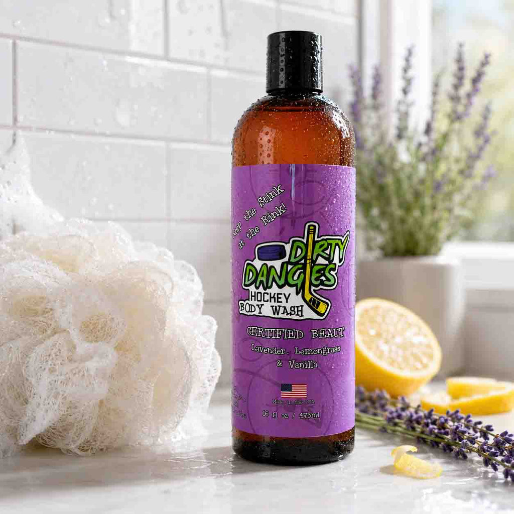 Bottle of Dirty Dandies body wash with a purple label on a bathroom counter, surrounded by lemons and lavender.