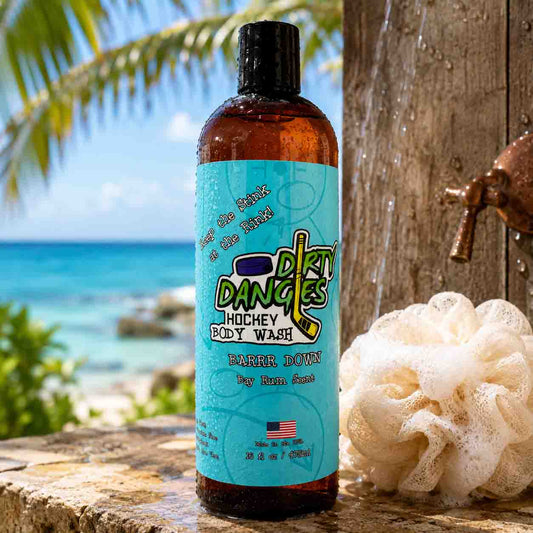 Bottle of Dirty Dangles Hockey Body Wash with a beach and palm tree in the background