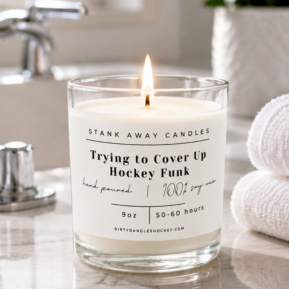 A white scented hockey candle in a bathroom with white towels. Trying to cover up hockey funk