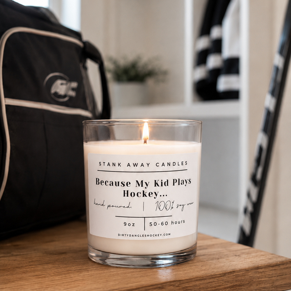 A white scented hockey candle on a wooden bench with hockey gear. Because my kid plays hockey.... 
