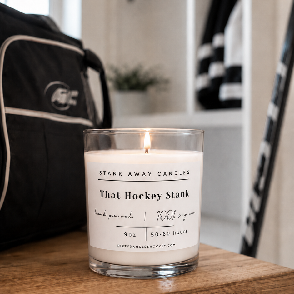 A white scented hockey candle on wooden bench with hockey gear. That hockey stank.