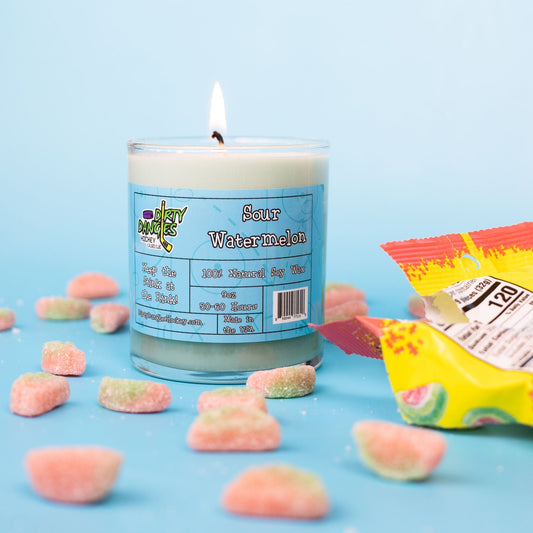 A green dirty dangles natural hockey candle sour watermelon scent on a blue background with sour watermelon candies