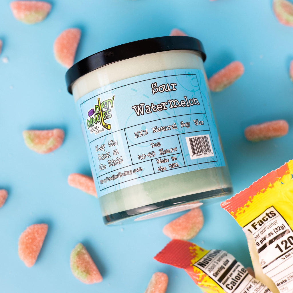 A green dirty dangles natural hockey candle sour watermelon scent on a blue background with sour watermelon candies