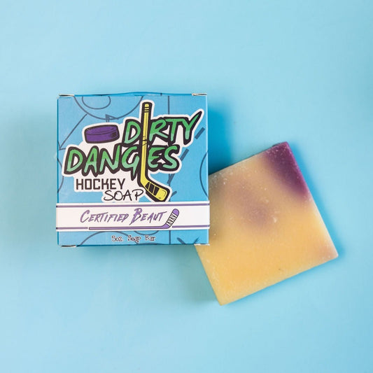 A yellow and purple bar of dirty dangles hockey soap Certified Beaut scent on a blue background with a blue box