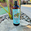 A bottle of dirty dangles hockey body wash 2 games on the beach scent on a rock with a tropical background.