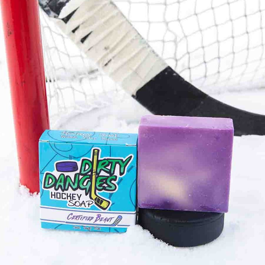 A purple soap bar on a snowy background with  a hockey stick, puck and goal. Certified Beaut
