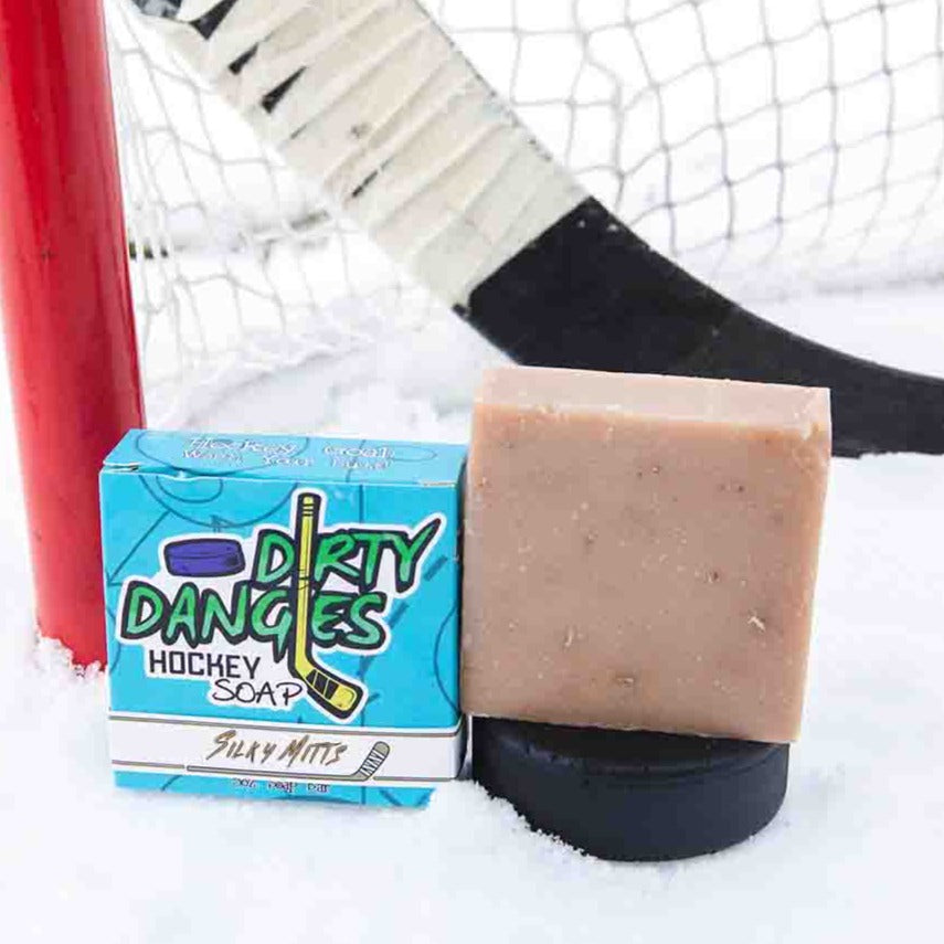 A Tan soap bar on a snowy background with  a hockey stick, puck and goal. Silky Mitts