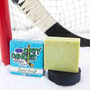 A green soap bar sits in the snow with a hockey goal, hockey puck and a hockey stick. Tendies Only
