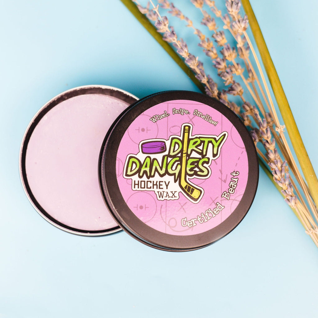 A tin of dirty dangles girls and womens hockey stick wax on a blue background with lavender and lemongrass