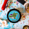A tin of Dirty Dangles Hockey Stick Wax Grandma's Cookies Scent sits on a blue background surrounded by sprinkles and baking supplies