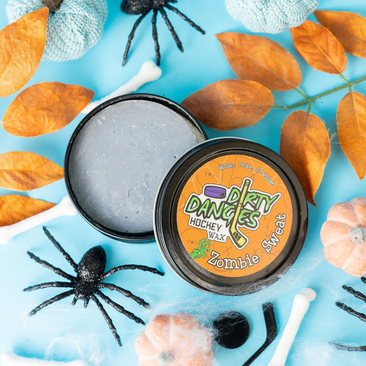 A tin of Halloween dirty dangles hockey zombie sweat pumpkin spice stick wax on a spooky background with spiders and pumpkins