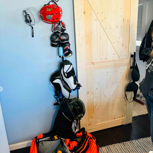 Hockey gear and a bottle of stank fighter hockey gear deodorizer hanging on an Utty hockey gear drying rack.