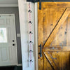 A 6 hook utty portable hockey gear drying rack hanging from the rail  of a wooden sliding door.