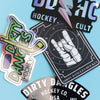 4 assorted dirty dangles hockey stickers on a blue background.
