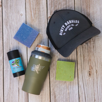 2 bars of hockey soap, a Tactical Green 2 in 1 drink tumbler can holder, a stick of dirty dangles natural deodorant and a dirty dangles hockey co. hat on a wood background.