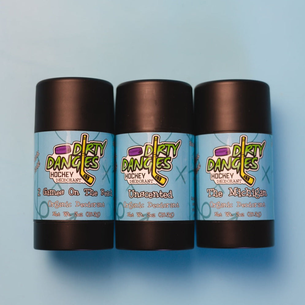 3 tubes of dirty dangles natural handmade deodorant on a blue background. 2 games on the beach, unscented, the michigan.