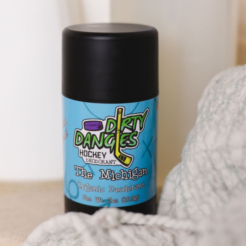 A tube of dirty dangles natural probiotic deodorant in a bathroom with soap