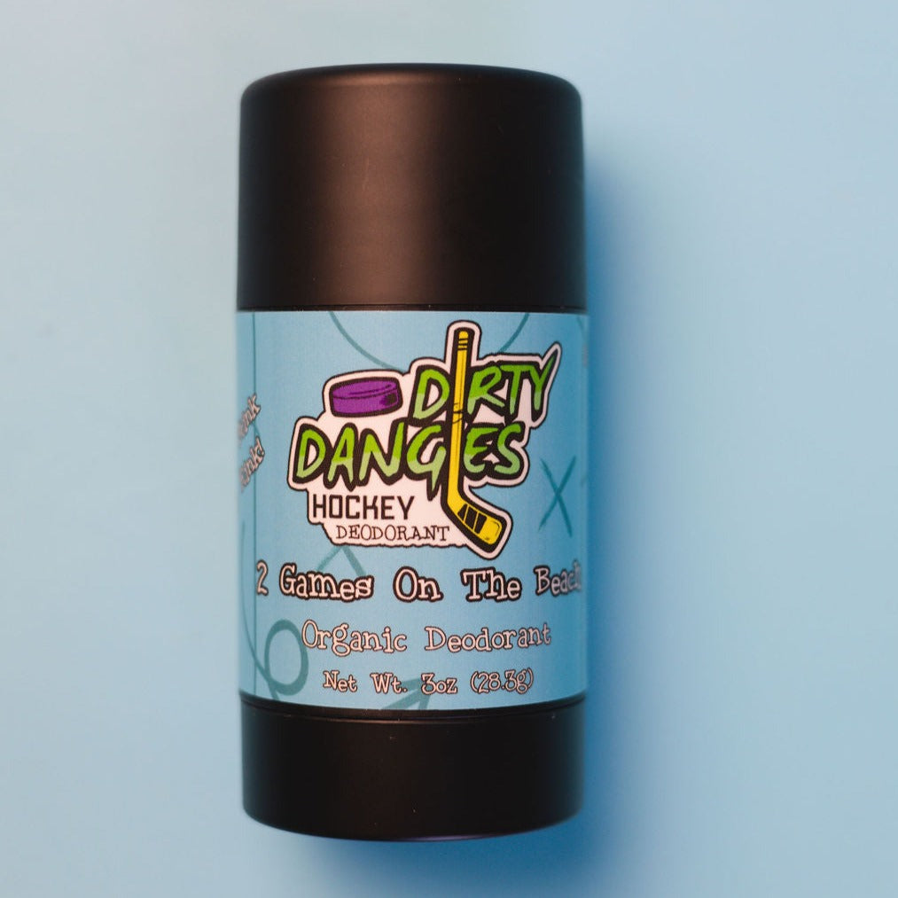 A tube of dirty dangles natural probiotic deodorant on a blue background. 2 Games on the Beach scent