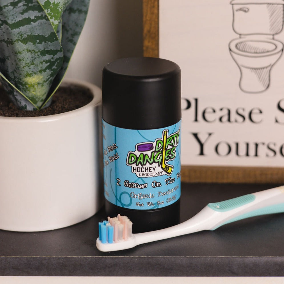 A tube of dirty dangles natural probiotic deodorant in a bathroom with a plant and a toothbrush.