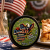 A tin of dirty dangles screamin eagle 4th of july stick wax on a picnic table with apple pie and american flags