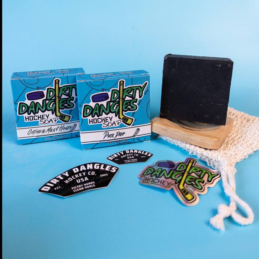DIrty Dangles hockey soap starter bundle. 2 Bars of soap, an exfoliating soap bag, soap dish and stickers sit on a blue background