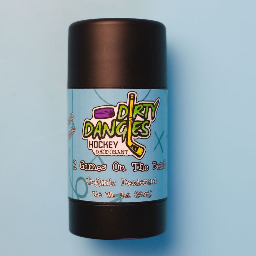 A tube of dirty dangles aluminum-free natural probiotic deodorant on a blue background. 2 Games on the Beach scent