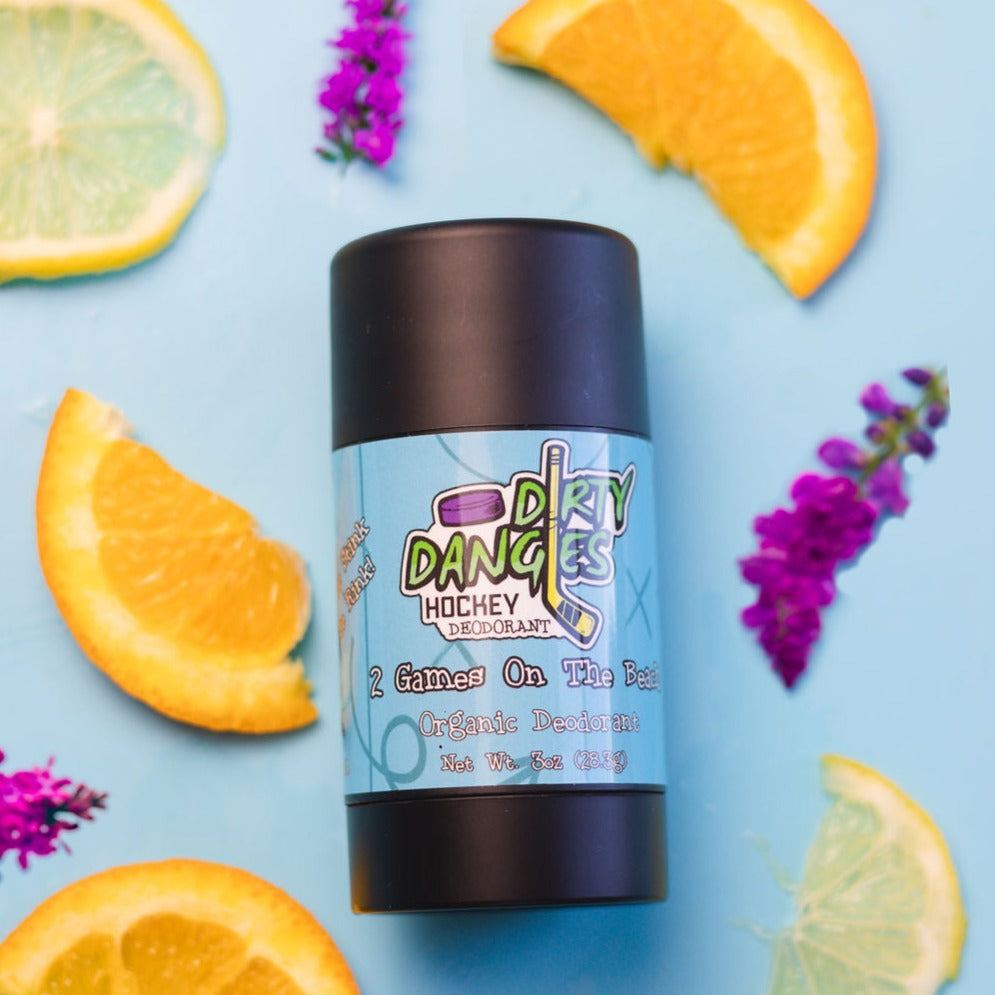 A tube of dirty dangles alumium-free 2 games on the beach tropical citrus scented natural hockey deodorant on a blue background with lemons and lavender