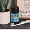 A tube of dirty dangles aluminum-free natural probiotic deodorant in a bathroom with a plant and a toothbrush.