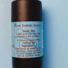 the back of a tube of aluminum-free dirty dangles natural probiotic deodorant on a blue background. Natural probiotic deodorant