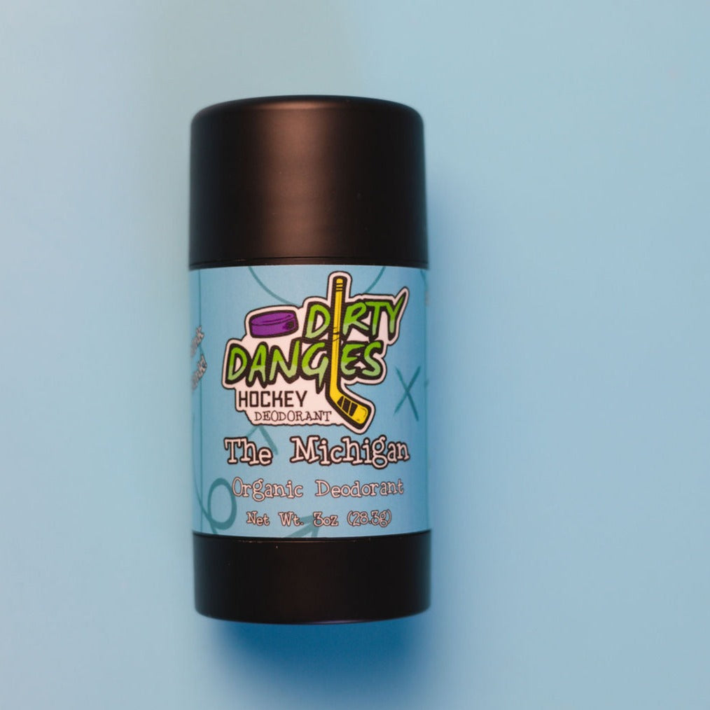 A tube of dirty dangles aluminum-free natural probiotic deodorant on a blue background. The Michigan scent