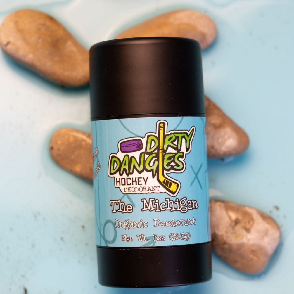 A tube of dirty dangles aluminum-free the michigan fresh scented natural hockey deodorant on a blue background with water and rocks