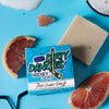 A white and orange beer league hero grapefruit pale ale soap bar with a blue soap box on a blue background with grapefruit slices.