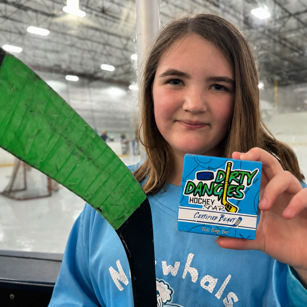 A young femle hockey player holding a certified beaut lavender lemongrass girl's soap bar.